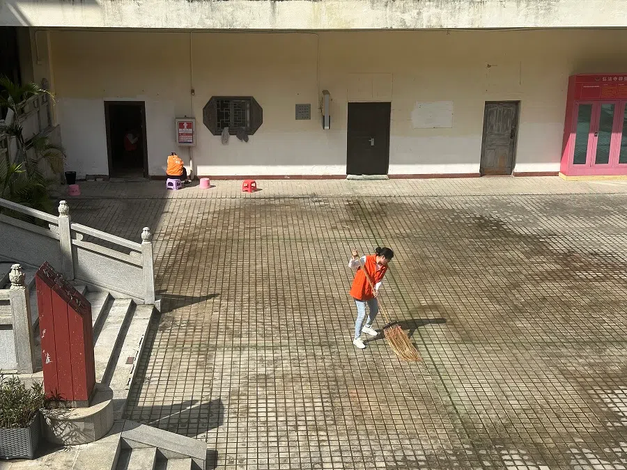 A volunteer sweeping the floor at Hongfa Temple in Shenzhen.