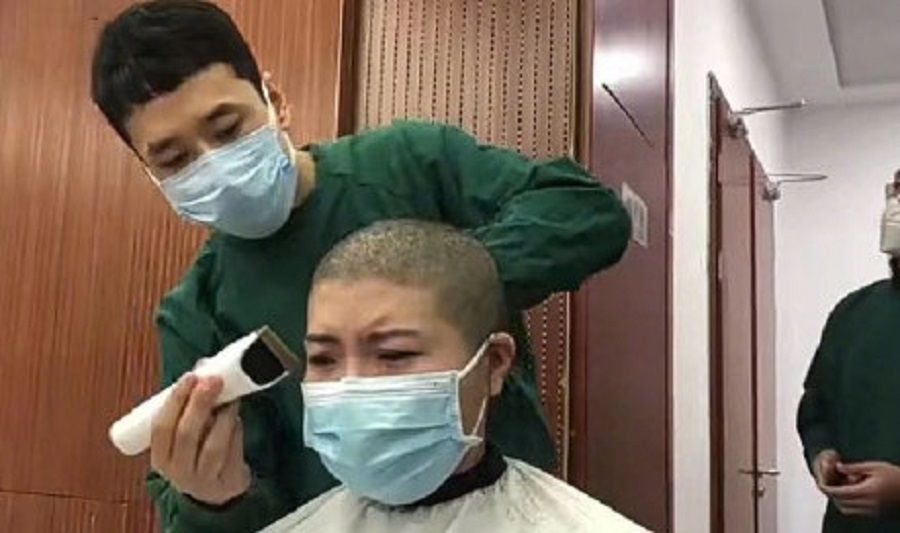 A nurse in tears as her head was shaved bald. (Weibo)