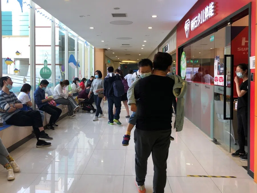 A man carries a sleepy child in the corridors of a mall with centres offering extra lessons to children.