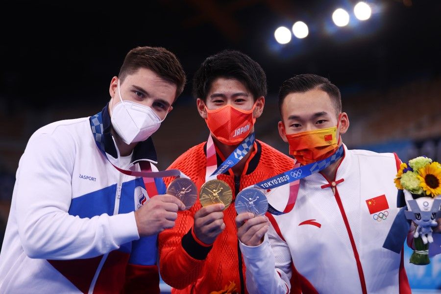 Gymnasts Daiki Hashimoto of Japan (centre), Xiao Ruoteng of China (right) and Nikita Nagornyy of the Russian Olympic Committee pose with their medals from the men's individual all-around event in artistic gymnastics, 28 July 2021. (Lindsey Wasson/Reuters)