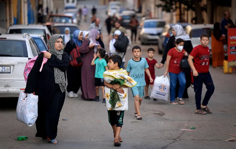 Palestinians carrying their belongings flee to safer areas in Gaza City after Israeli air strikes, on 13 October 2023. (Mahmud Hams/AFP)