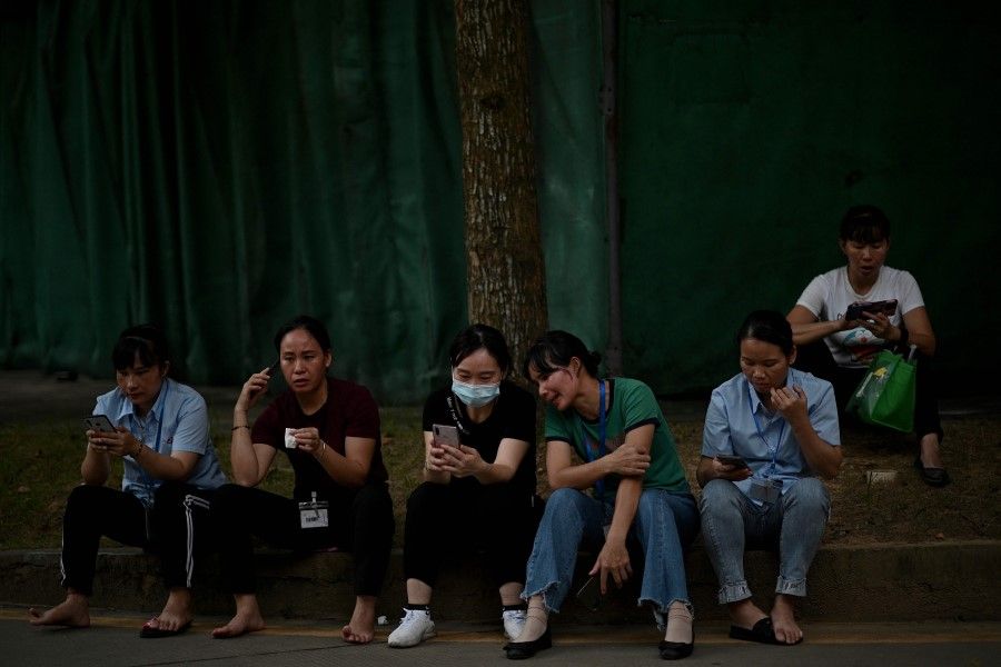 Workers at a television manufacturing company called Express Luck rest during a break at their factory in Shenzhen, in southeastern China on 29 September 2021. (Noel Celis/AFP)