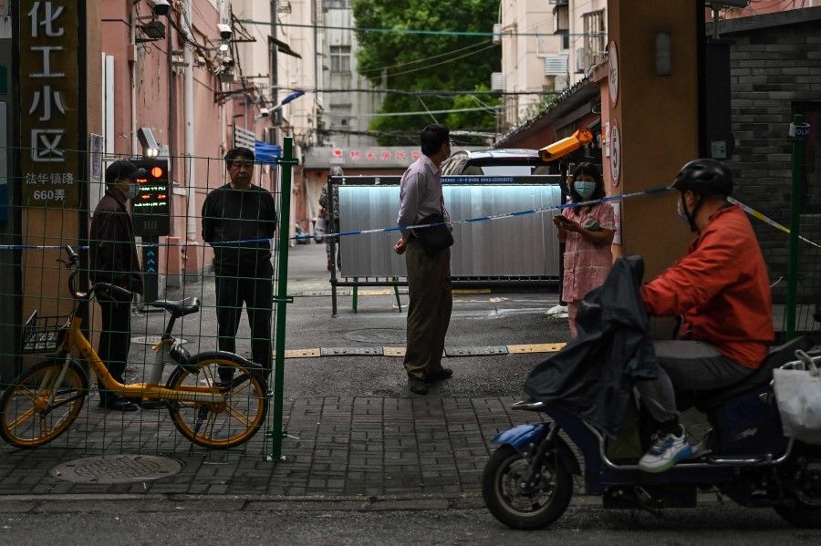 Neighbours are seen at the entrance of a compound in lockdown in the Changning district, after new Covid-19 cases were reported in Shanghai, on 8 October 2022. (Hector Retamal/AFP)