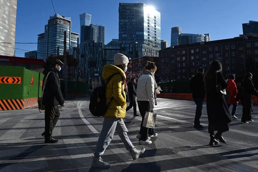 People cross a road in Beijing, China, on 8 December 2024. (Greg Baker/AFP)