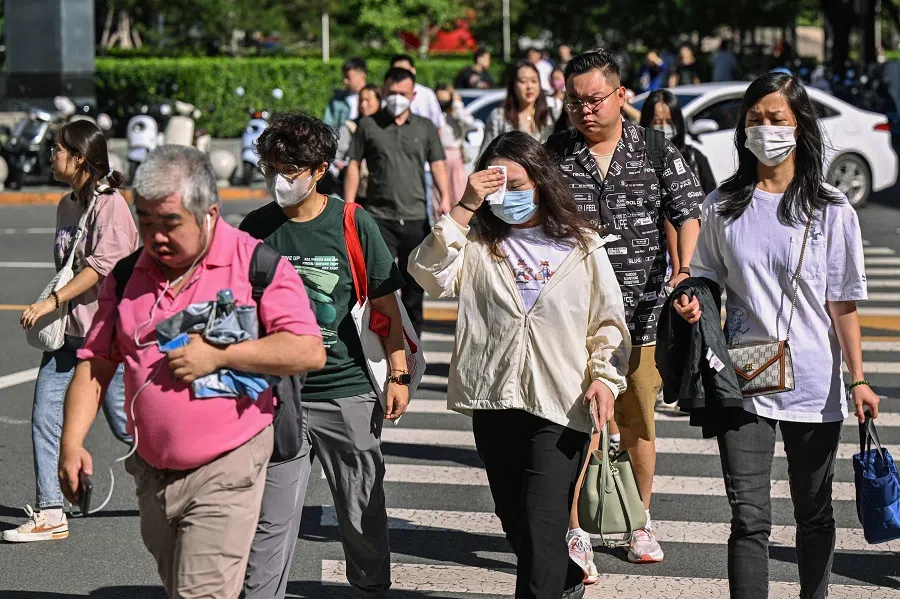 People cross a street in Beijing on 27 August 2024. (Adek Berry/AFP)