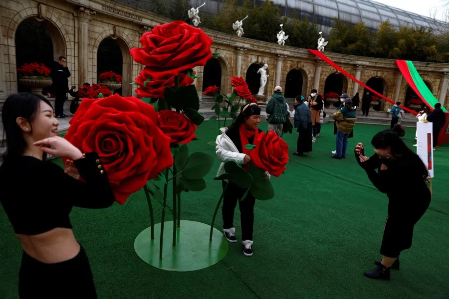 People pose for pictures in front of giant rose installations on Valentine's Day in Beijing, China, 14 February 2023. (Tingshu Wang/Reuters)