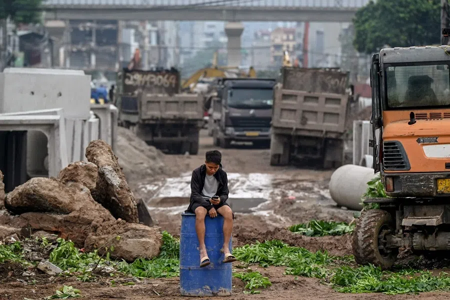 A man uses his phone at a road expansion construction site in Hanoi on 4 August 2026.