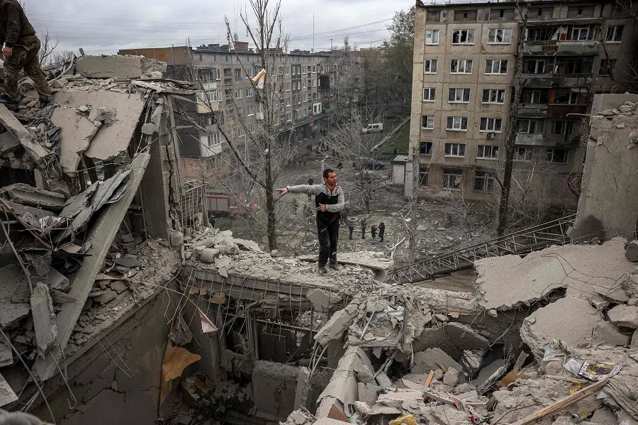 A volunteer gestures on top of a partially destroyed residential building after a shelling in Sloviansk, Donetsk region, Ukraine, on 14 April 2023. (Anatolii Stepanov/AFP)
