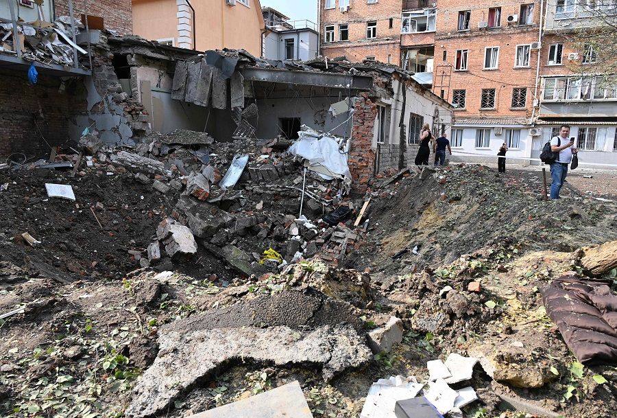 Local residents stand next to a crater after shelling in the centre of Kharkiv, Ukraine, on 11 August 2022, amid the Russian military invasion of Ukraine. (Sergey Bobok/AFP)