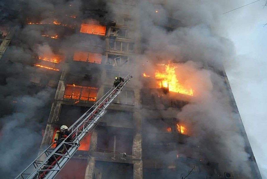 In this handout picture taken and released by the State Emergency Service of Ukraine on 15 March 2022, firefighters work to extinguish a fire in a housing block hit by shelling in the Sviatoshynsky district in western Kyiv. (AFP)