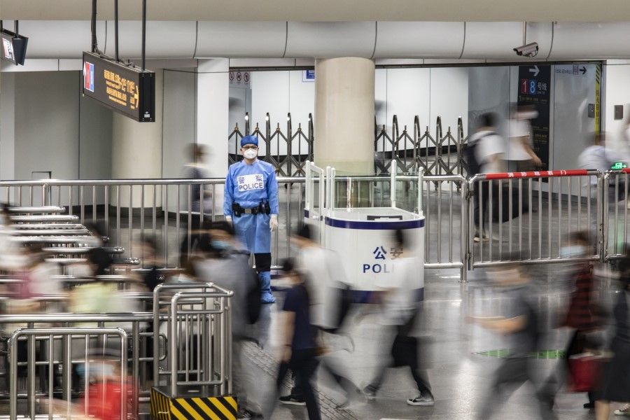 Commuters walk past a police officer wearing protective gear at a subway station in Shanghai, China, on 1 June 2022. (Qilai Shen/Bloomberg)