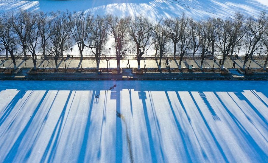 This aerial photo taken on 3 December 2022 shows a person walking along a frozen lake after snowfall in Shenyang, Liaoning province, China. (AFP)