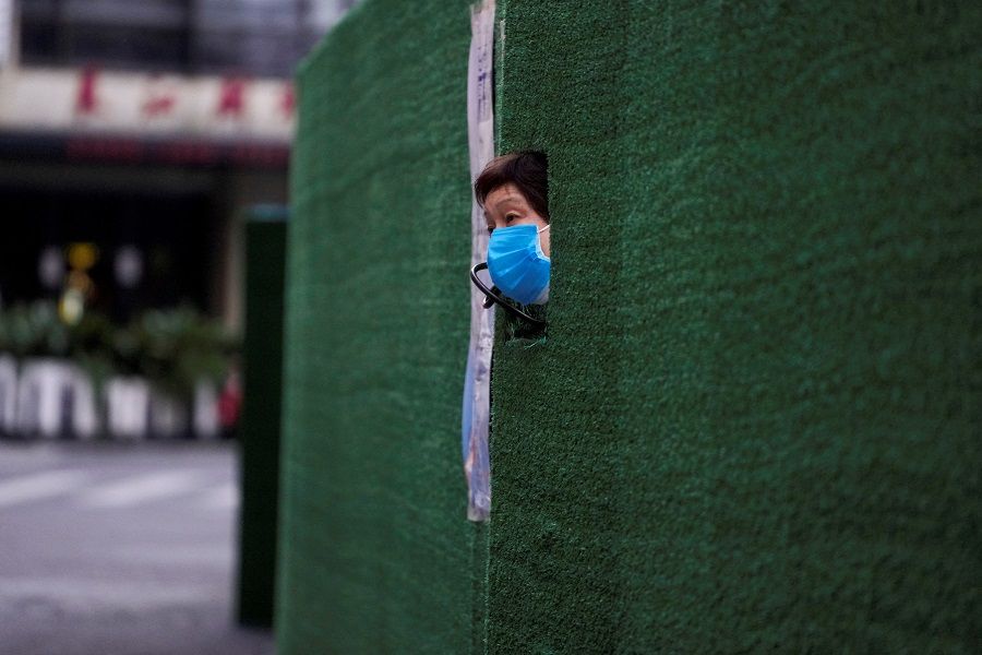 A resident looks out through a gap in the barrier at a residential area during lockdown, amid the Covid-19 pandemic, in Shanghai, China, 6 May 2022. (Aly Song/Reuters)