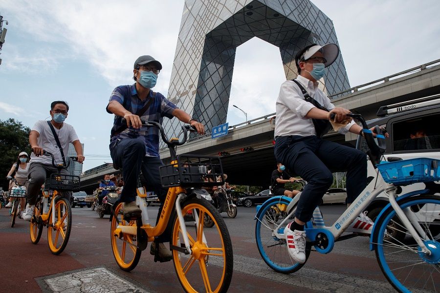 People ride shared bicycles past the CCTV headquarters in the Central Business District in Beijing, China, on 4 August 2020. (Thomas Peter/Reuters)