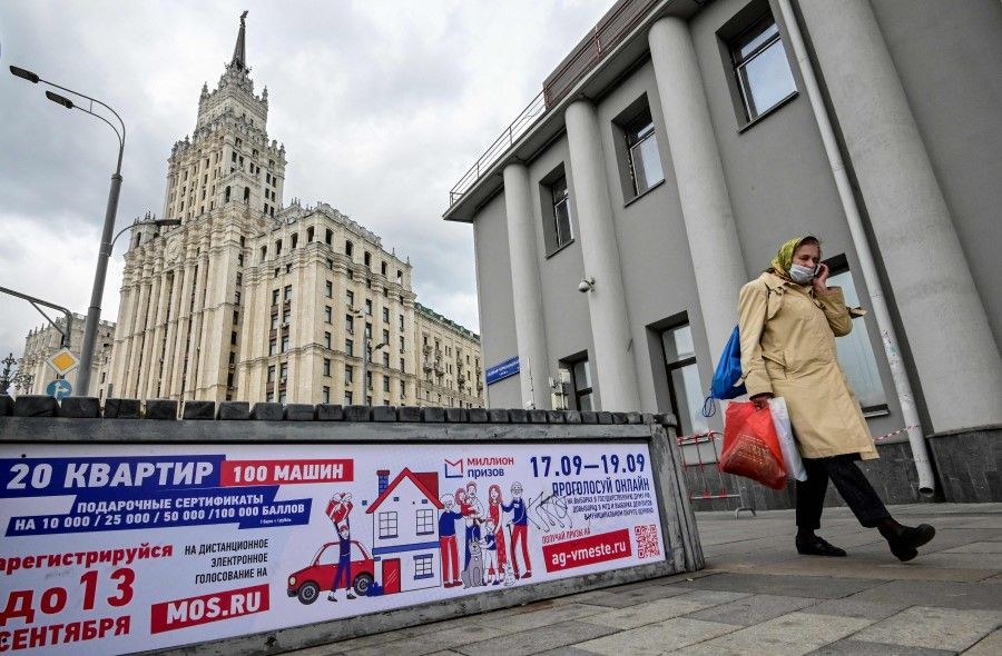A woman speaks on a mobile phone walking past a poster announcing the upcoming Russian parliamentary and local elections in Moscow on 14 September 2021. (Yuri Kadobnov/AFP)
