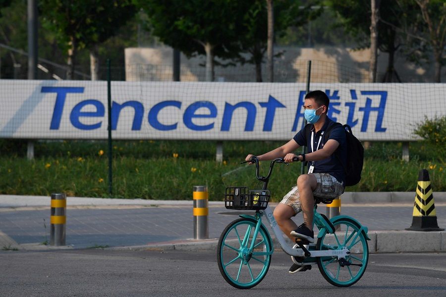 A man walks past a sign for Tencent, the parent company of Chinese social media giant WeChat, outside the Tencent headquarters in Beijing on 7 August 2020. (Greg Baker/AFP)