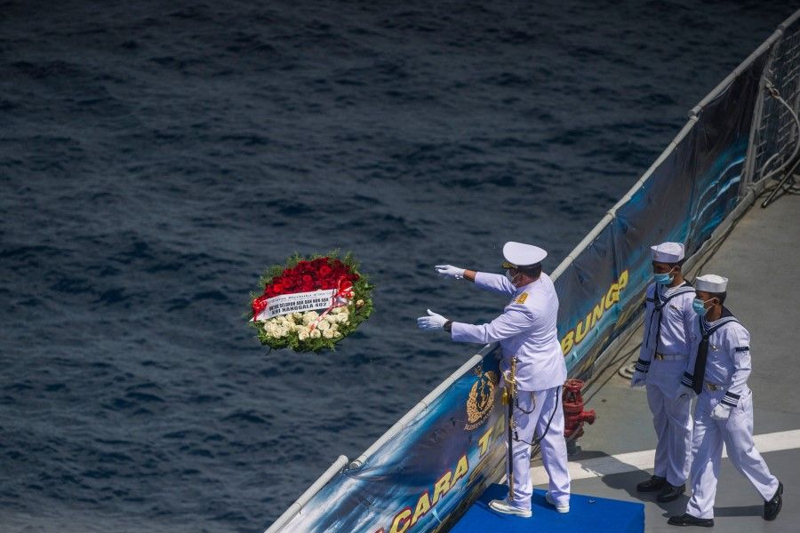 In this file photo taken on 30 April 2021, a naval officer throws a flower bouquet into the sea during a remembrance ceremony for the crew of the Indonesian navy submarine KRI Nanggala that sank on 21 April during a training exercise, on the deck of the hospital ship KRI Dr. Soeharso off the coast of Bali. (Juni Kriswanto/AFP)