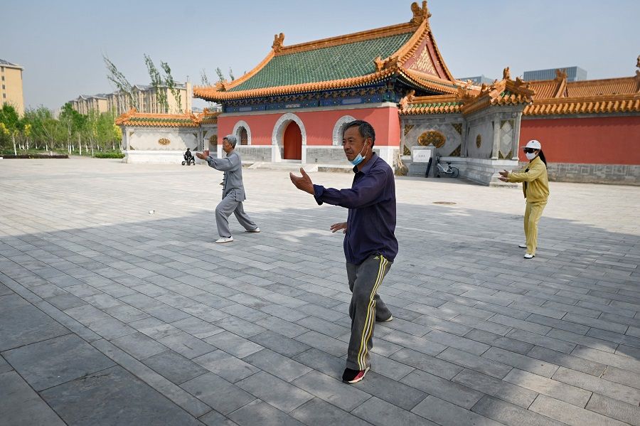 This picture taken on 30 April 2020 shows people wearing face masks, amid concerns of the Covid-19 coronavirus, practising Tai Chi at a park in Beijing. (Wang Zhao/AFP)