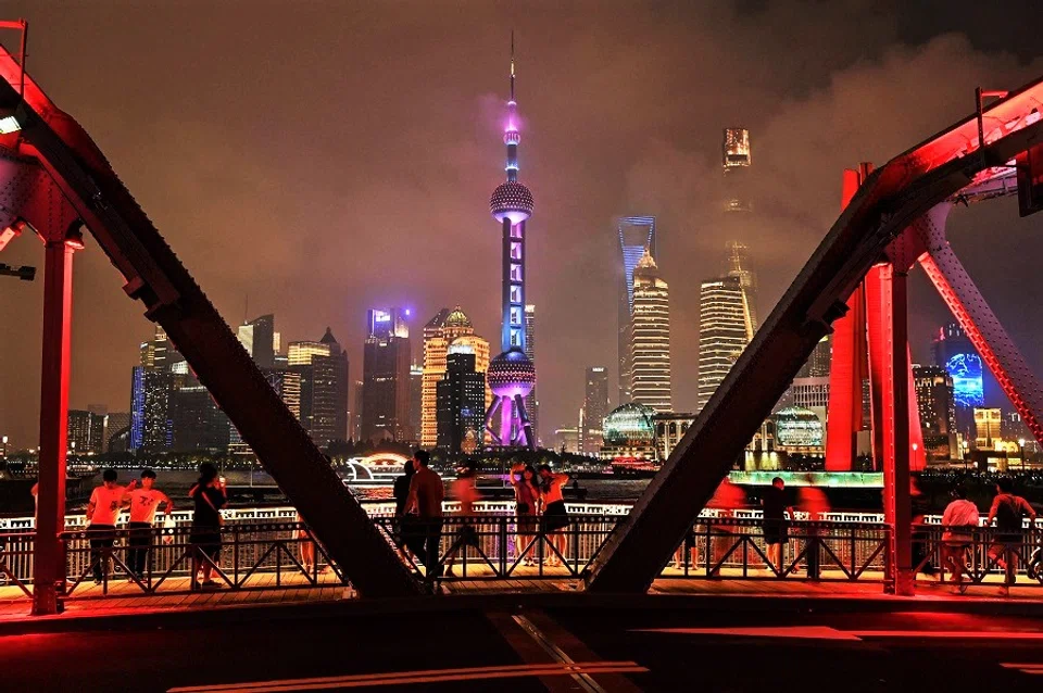 This photo taken on 13 June 2021 shows people looking at the city view from a bridge in Shanghai, China. (Hector Retamal/AFP)