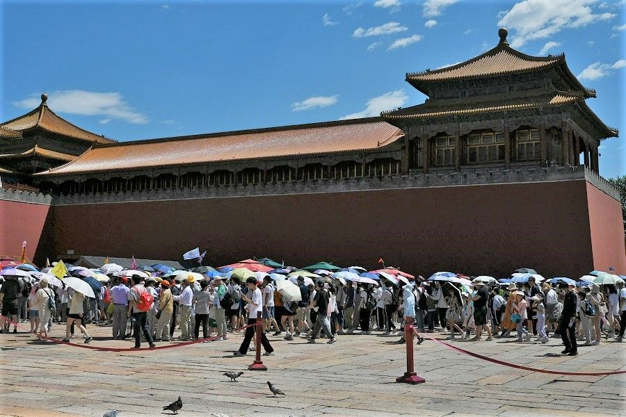 Visitors shelter under umbrellas as they line up to enter the Forbidden City on a hot day in Beijing, China, on 9 July 2023. (Greg Baker/AFP)