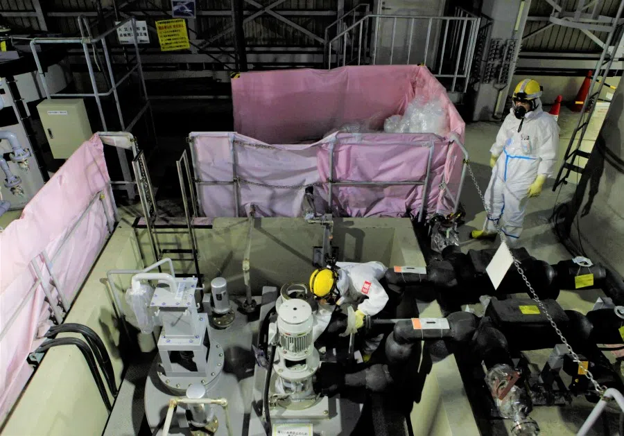 Employees of Tokyo Electric Power Co's (TEPCO) wearing protective suits and masks are seen inside a radiation filtering Advanced Liquid Processing Systems, known as ALPS, at tsunami-crippled Fukushima Daiichi nuclear power plant in Okuma town, Fukushima prefecture, Japan, 15 January 2020. (Aaron Sheldrick/Reuters)