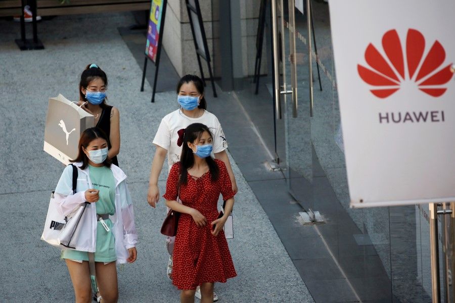 Women wearing face masks following the coronavirus disease (Covid-19) outbreak walk past a Huawei store at a shopping complex in Beijing, China, 14 July 2020. (Tingshu Wang/Reuters)