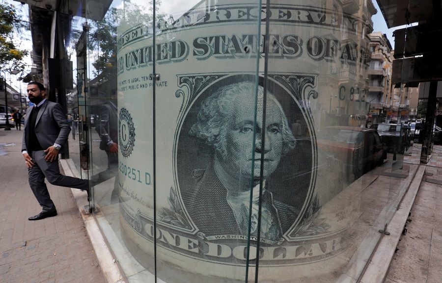 A man leaves a currency exchange bureau showing an image of the US dollar in Cairo, Egypt on 17 March 2020. (Amr Abdallah Dalsh/Reuters)