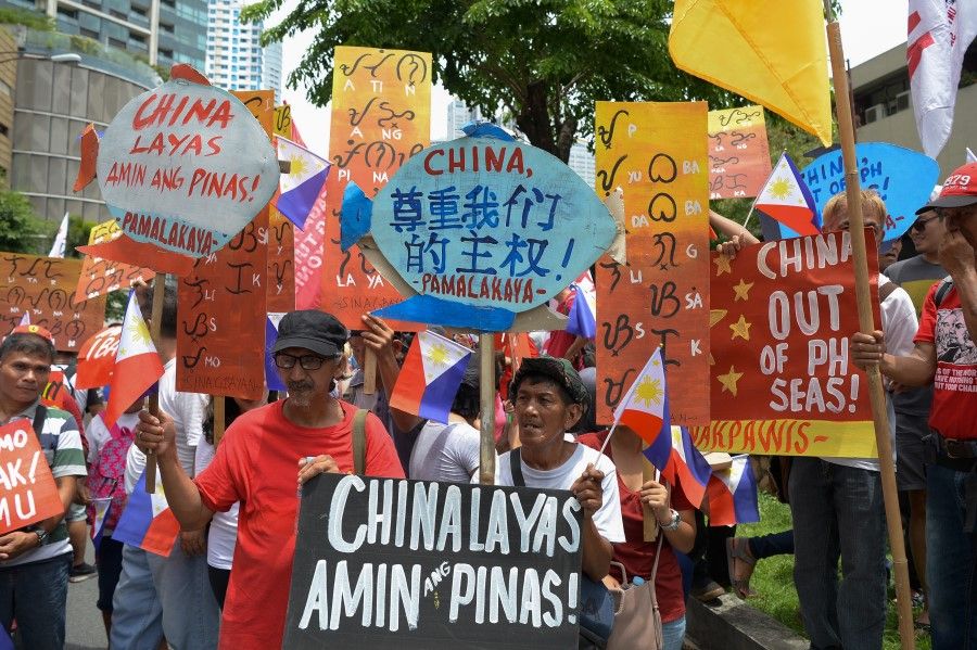 Activists hold placards with anti-China slogans during a protest in front of the Chinese consulate in Manila on 12 June 2019, against the Asian superpower's growing sway in the Philippines and as tensions rise over Beijing's presence in the disputed South China sea. (Ted Aljibe/AFP)