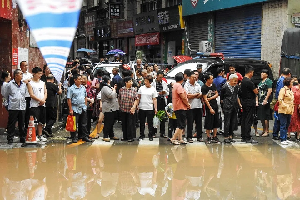 This photo taken on 6 September 2021 shows residents looking at a flooded area after heavy rainfalls in Quxian county, Dazhou city, Sichuan province, China. (STR/AFP)