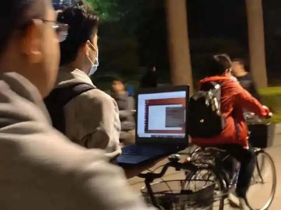 Screenshot of a widely circulated video of a Tsinghua University student riding his bicycle while holding an open laptop. (Internet)