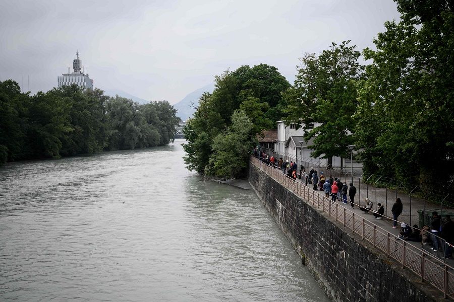 People in need queue along Arve river at a free food distribution center in Geneva on 16 May 2020. (Fabrice Coffrini/AFP)