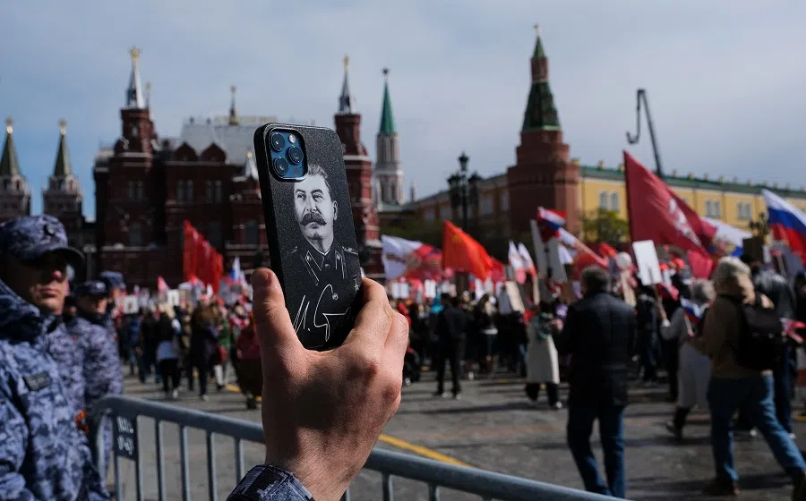 A law enforcement officer holds a phone with a portrait of Soviet leader Joseph Stalin during the Immortal Regiment march on Victory Day, in Moscow, Russia, 9 May 2022. (Shamil Zhumatov/Reuters)