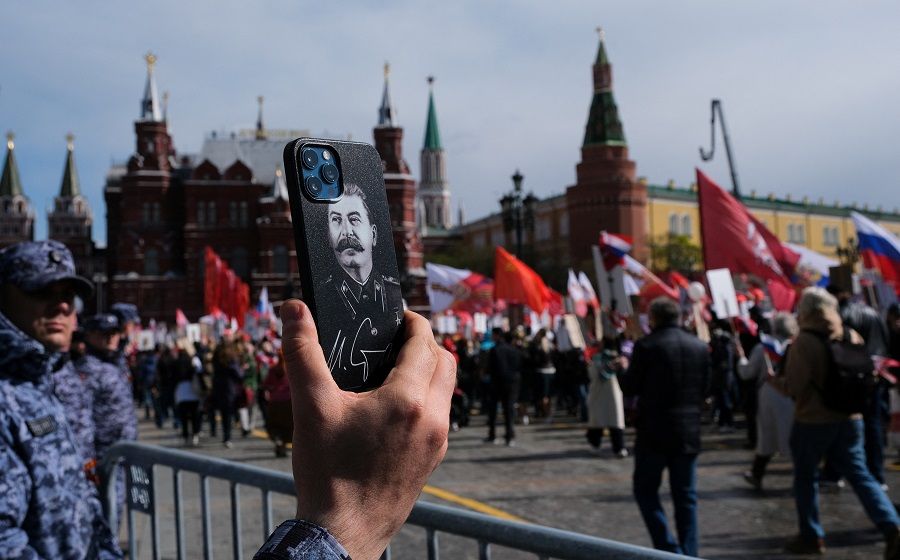 A law enforcement officer holds a phone with a portrait of Soviet leader Joseph Stalin during the Immortal Regiment march on Victory Day, in Moscow, Russia, 9 May 2022. (Shamil Zhumatov/Reuters)