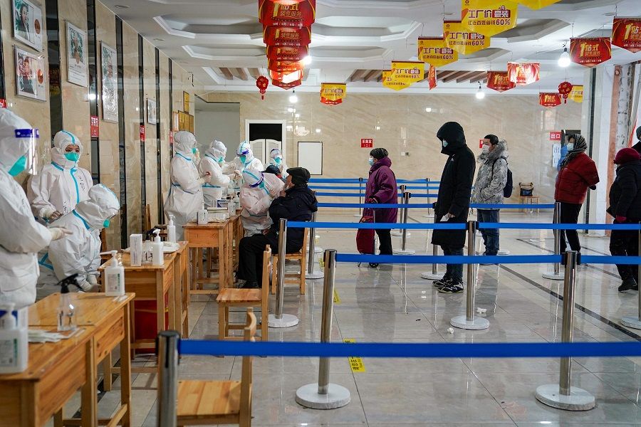 A medical worker takes a swab sample from a man as people queue to get tests for the Covid-19 coronavirus at an office building in Harbin, Heilongjiang province, China, on 14 January 2021. (STR/AFP)
