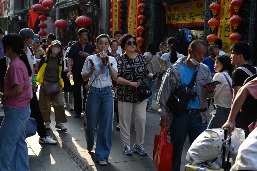 People walk through a traditional shopping street in the Qianmen area of Beijing on the last day of the five-day Labour Day holiday on 3 May 2023. (Greg Baker/AFP)