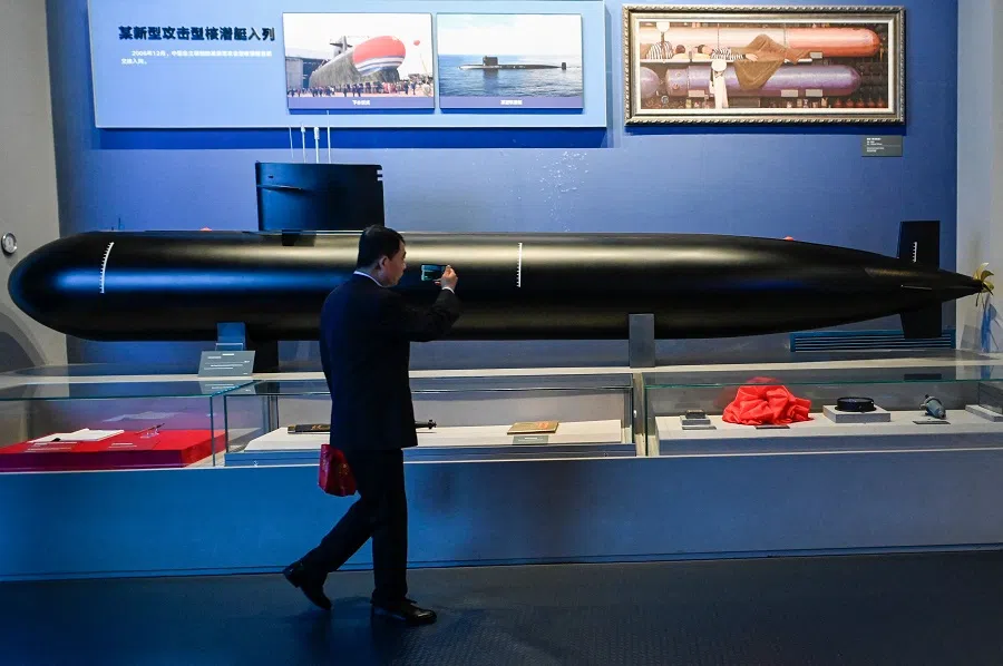 This picture taken during a media tour organised by the PLAN to mark its 75th founding anniversary, shows a man taking a picture of a model of a Chinese Navy submarine at the PLA Naval Museum in Qingdao, Shandong province, China, on 23 April 2024.  (Wang Zhao/AFP)
