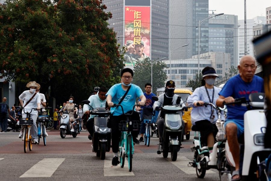 People ride vehicles in Beijing, China, 4 August 2022. (Thomas Peter/Reuters)