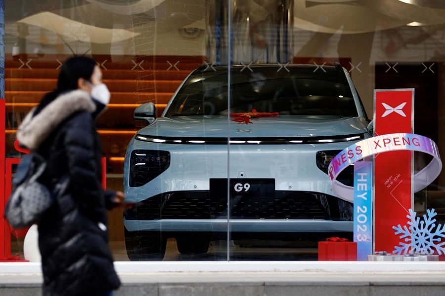 A person walks past an XPeng G9 electric vehicle (EV) at its flagship store in Beijing, China, 2 February 2023. (Tingshu Wang/Reuters)
