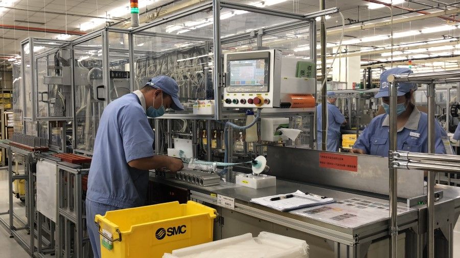 Workers at SMC (China) preparing machine components.