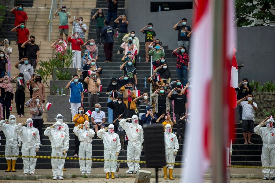 Medical workers wearing personal protective equipment (PPE) and patients salute, during the ceremony to mark the country's 76th Independence Day, at the Athletes Village Emergency Hospital for coronavirus disease (COVID-19) in Jakarta, Indonesia, 17 August 2021. (M Risyal Hidayat/via Reuters)