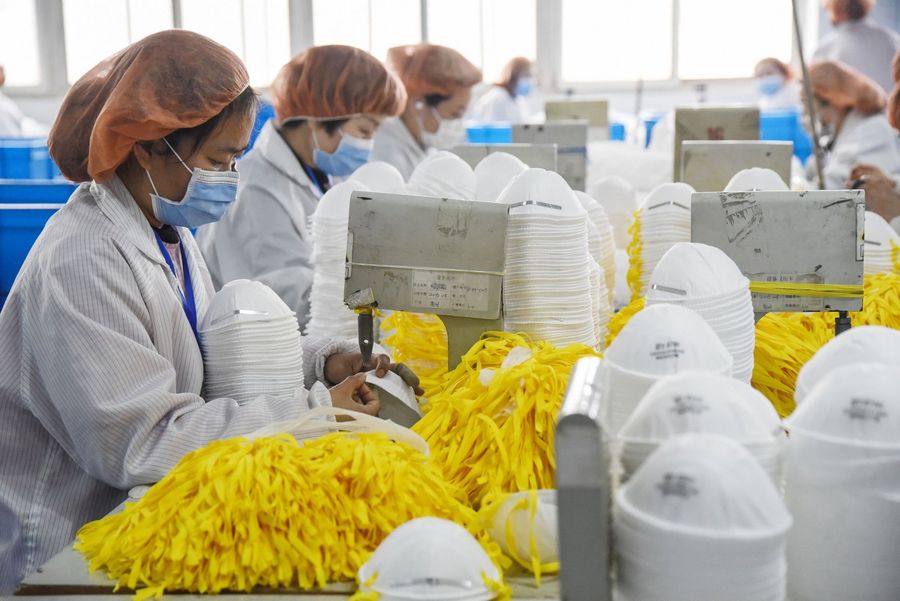 This photo taken on 28 February 2020 shows workers producing face masks at a factory in Handan, Hebei, China. (STR/AFP)