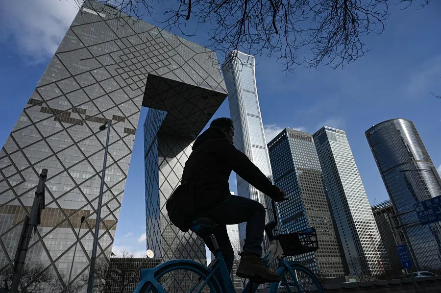 A man rides a bicycle on a street at the central business district in Beijing on 17 March 2025. (Jade Gao/AFP)