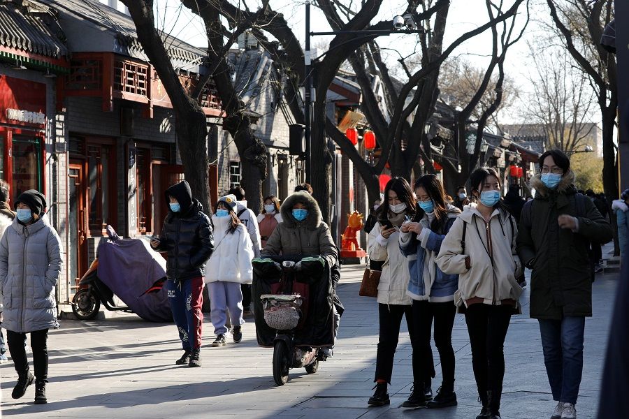 People wearing face masks walk along Nanluoguxiang alley, in Beijing, China, 16 January 2021. (Tingshu Wang/Reuters)