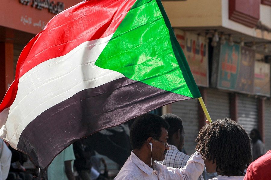A man waves a Sudanese national flag while taking part in a protest march against a deal agreed the previous month between military leaders and some civilian factions on a two-phase political process since the 2021 military coup, headed towards the presidential palace in Sudan's capital Khartoum on 24 January 2023. (AFP)