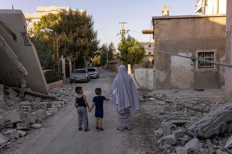 A woman and her two children walk along a street heavily damaged by Israeli air strikes in Baalbek, in Lebanon’s eastern Bekaa Valley, on 9 October 2024, amid the ongoing war between Israel and Hezbollah. (Fabio Bucciarelli/AFP)