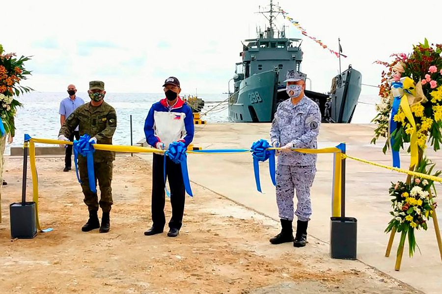 This handout photo received on 9 June 2020 from the Department of National Defense Philippines (DND), shows Defense secretary Delfin Lorenzana (centre) along with military officials cutting a ribbon during the inauguration ceremony of the newly constructed beach-ramp at Philippine-held Pag-asa Island also known as Thitu Island in the Spratly archipelagos. (Handout/Department National Defense Philippines (DND)/AFP)