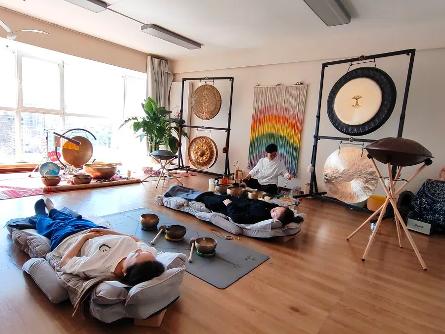 Young people lie down with their eyes closed at Yiyan natural therapy studio to immerse in a “lie-down concert” of sound therapy.