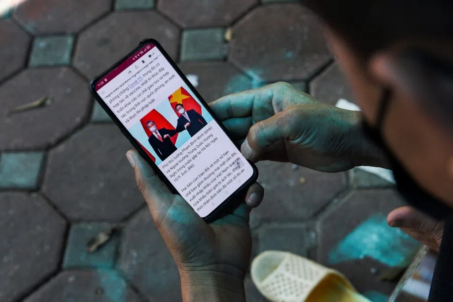 A man reads the news about Chinese foreign minister Wang Yi's visit to Vietnam, on a street in Hanoi, Vietnam, 11 September 2021. (Stringer/Reuters)