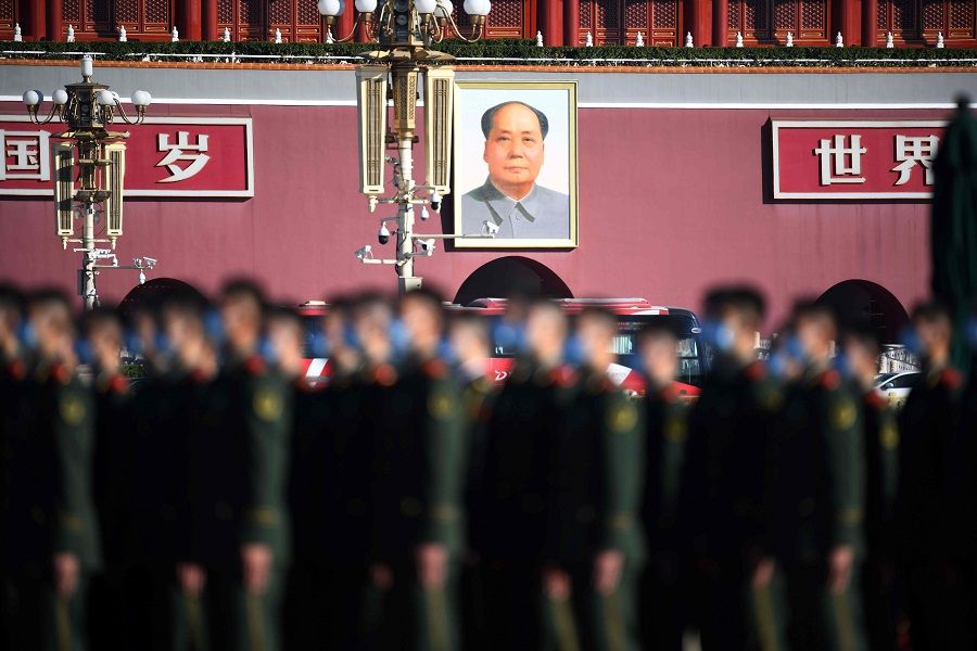 The portrait of late communist leader Mao Zedong is seen behind paramilitary police officers as they gather in Beijing's Tiananmen Square on 23 October 2020. (Noel Celis/AFP)