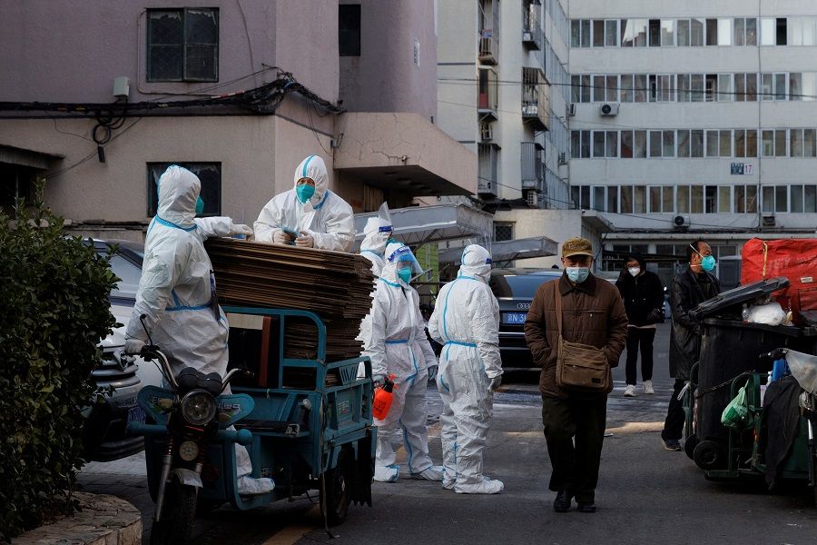 Pandemic prevention workers stand outside a building where residents do home quarantine, as Covid-19 outbreaks continue in Beijing, China, 8 December 2022. (Thomas Peter/Reuters)